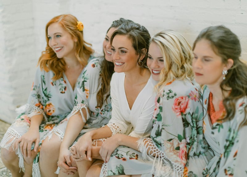 a bride and bridesmaids in floral robes smiling.