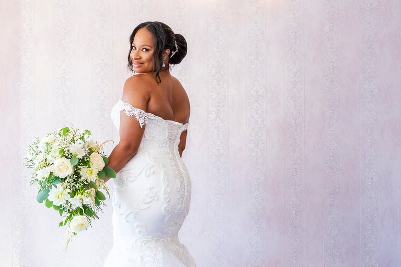 a bride smiles as she holds her bouquet and turns to face the camera.