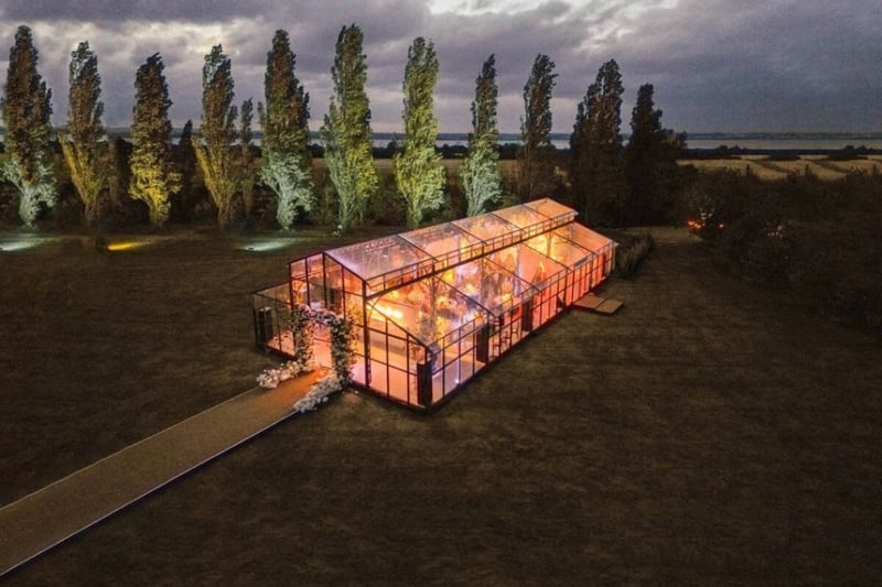 A glass wedding marquee illuminated at dusk