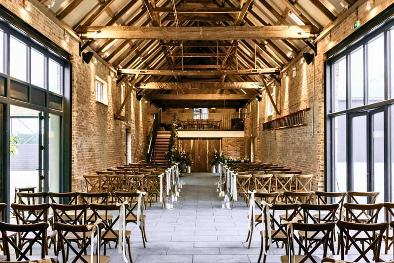 Converted brick barn wedding venue with mezzanine gallery and white aisle runner