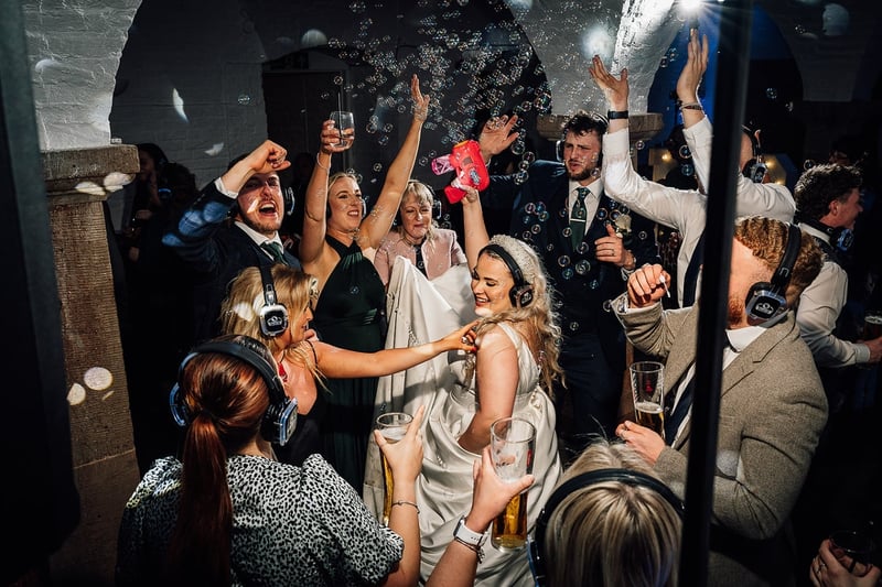 a bride and groom dance with their wedding guests in a silent disco and use a bubble machine.