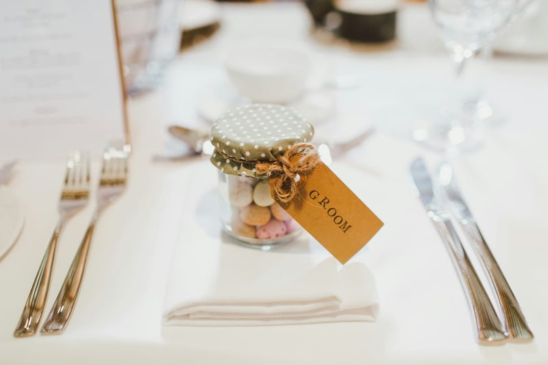 a small jar of sweets at a place setting with kraft paper label that reads 'groom'