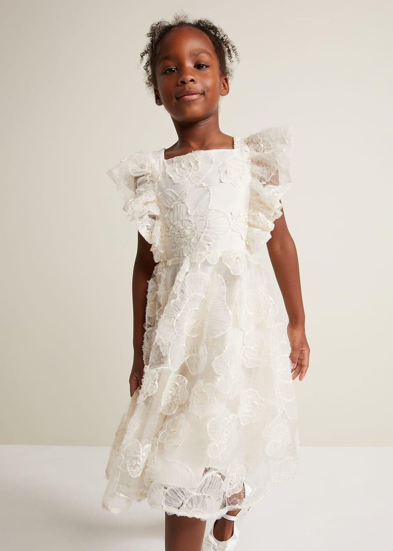 a child model wears a white floral flower girl dress.