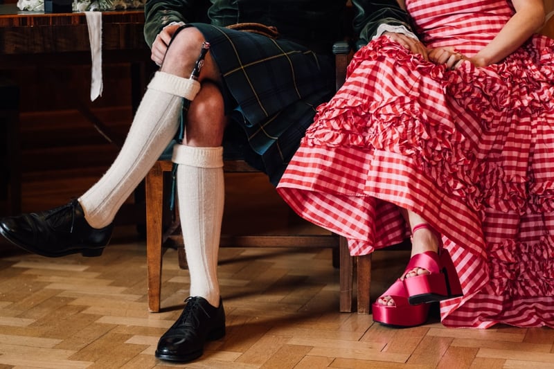 the lower part of a bride and groom's outfits, including a kilt and white socks and a red check-print wedding dress.