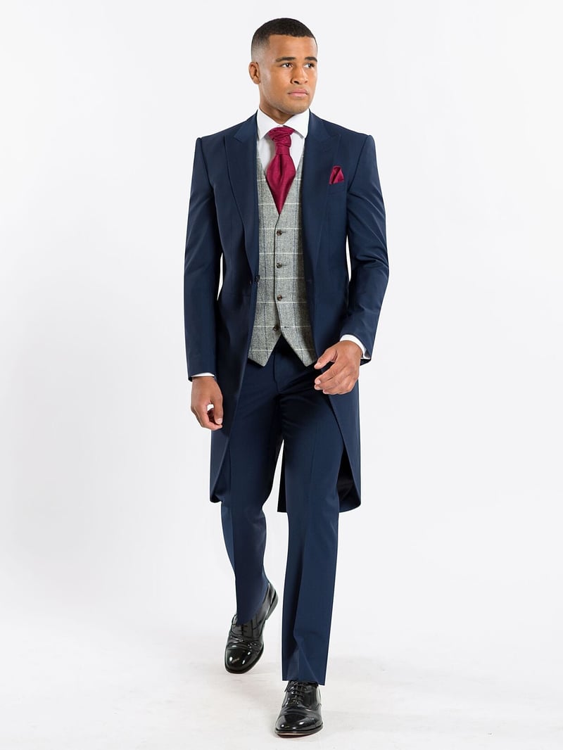 a male model wearing a navy morning suit with contrasting grey waistcoat and red tie.