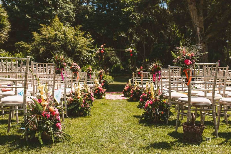 Tropical style garden with an outdoor wedding ceremony set up with brightly coloured flowers