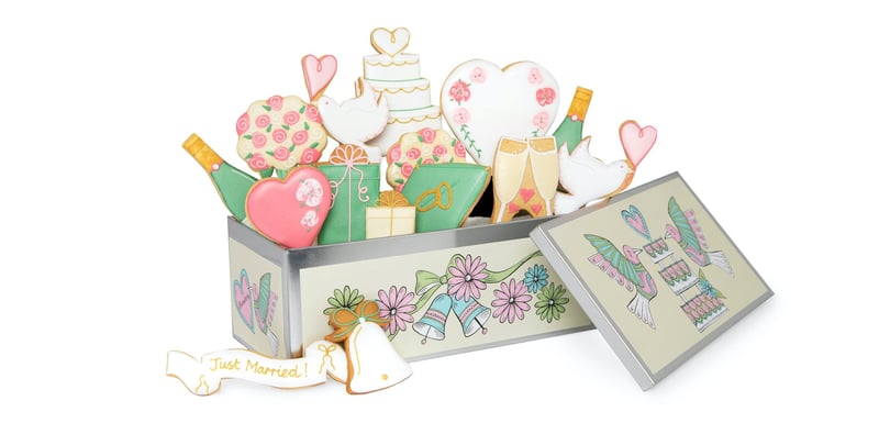 a colourful biscuit tin with lots of wedding-themed iced biscuits.