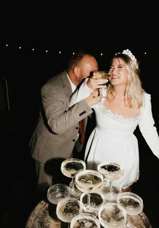 Bride and groom laughing by a champagne tower