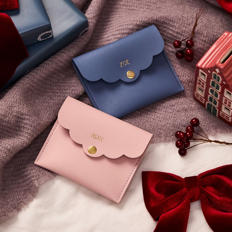 two scalloped mini faux leather pouches embossed with gold names.
