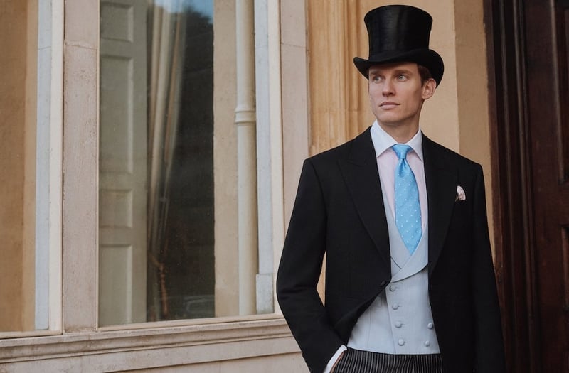 a model wearing a black morning suit with a pale blue waistcoat, blue tie and black top hat.