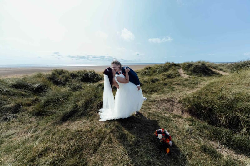 Bride and groom kissing on the sand dunes at a beach wedding