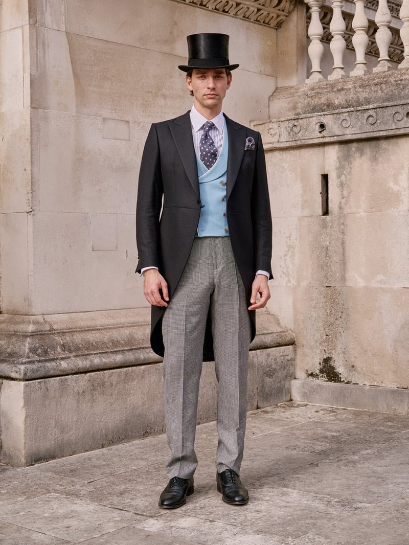 a male model standing outside a wedding venue wearing a morning suit with check print grey trousers, blue waistcoat and patterned tie.