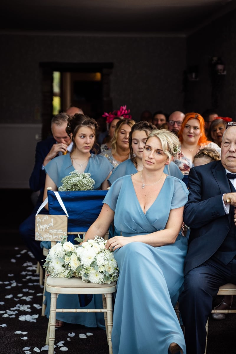 a bridesmaid in a blue dress looks on during the ceremony.