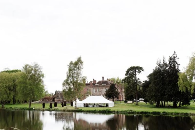 A white marquee set up in the grounds of ketteringham hall next to a lake