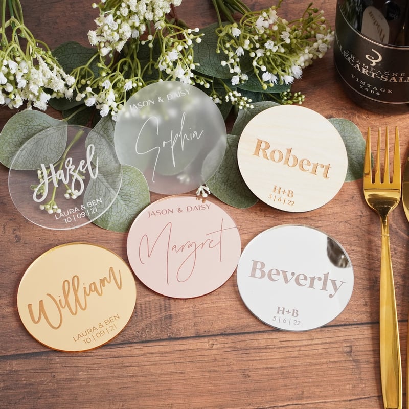 a selection of engraved personalised coasters on a wooden table.