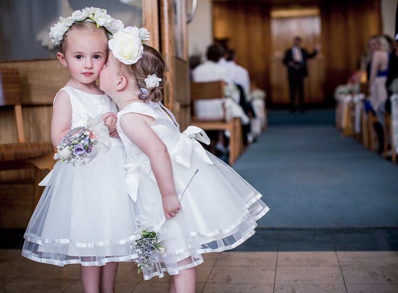 two young flower girls in white dresses holding flower wands.