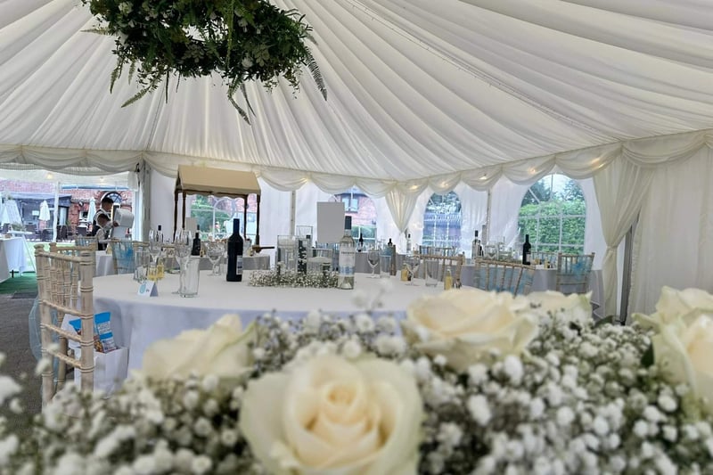 A white marquee set up for a wedding with floral decorations