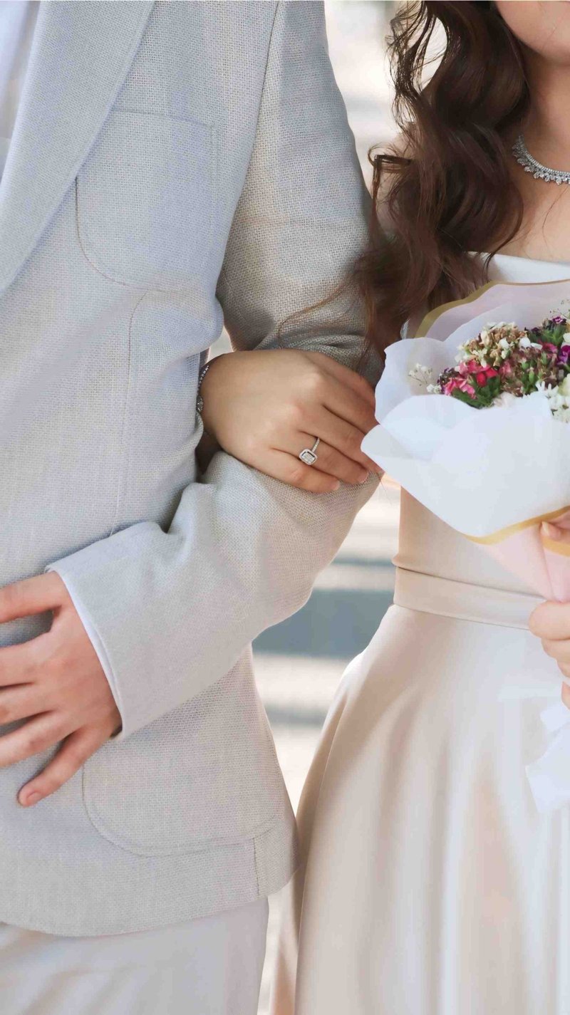 A closeup of a bride and groom embracing, showcasing wedding rings and bouquet