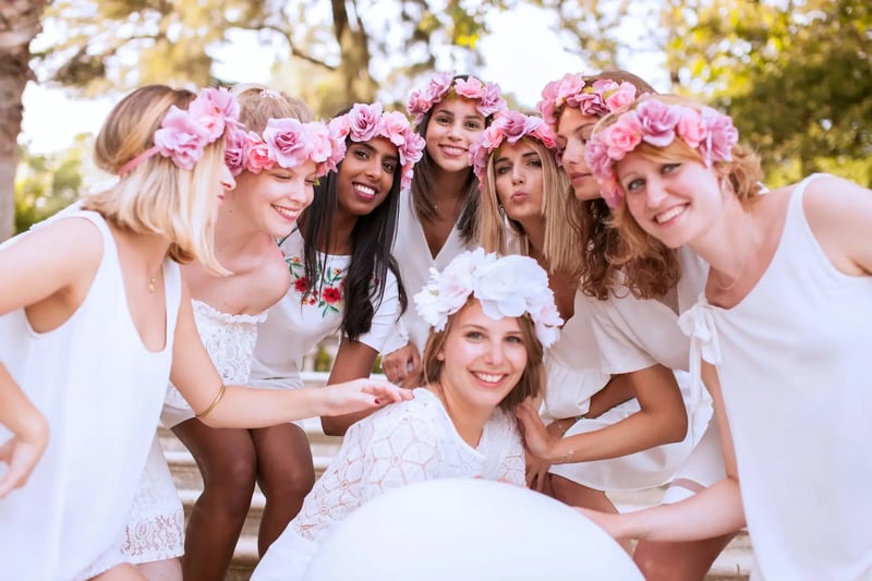 In Weiß gekleidete Frauen mit rosa Blumenring um den Kopf lächeln in die Kamera