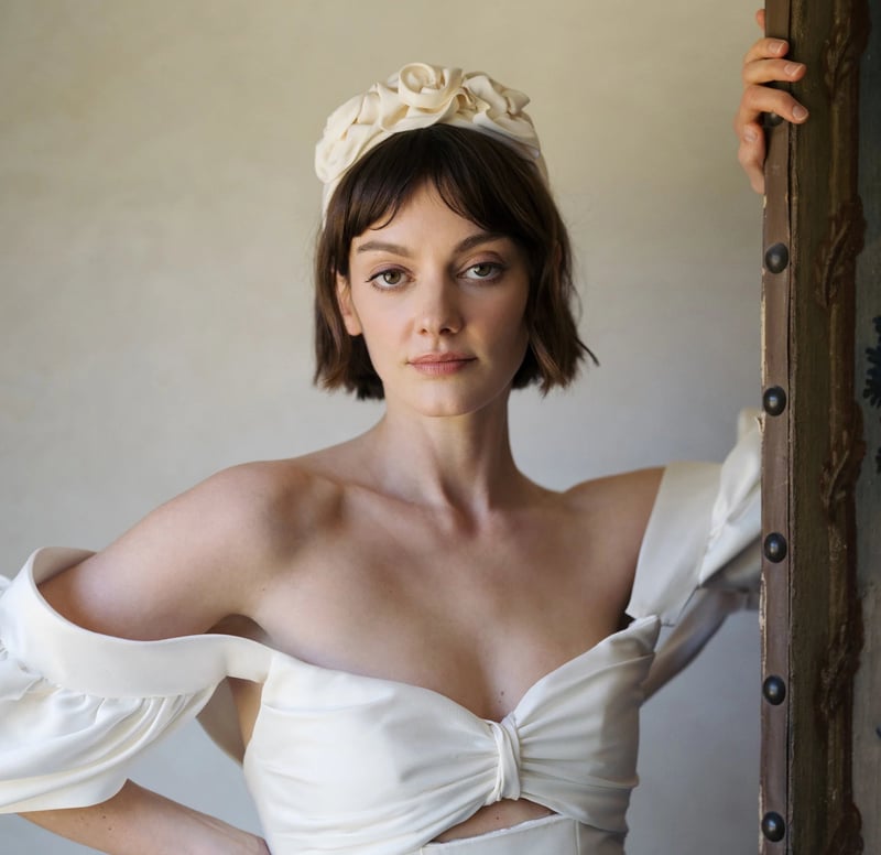 a brunette model with a short bob wears a silk wedding headband with flower detail.