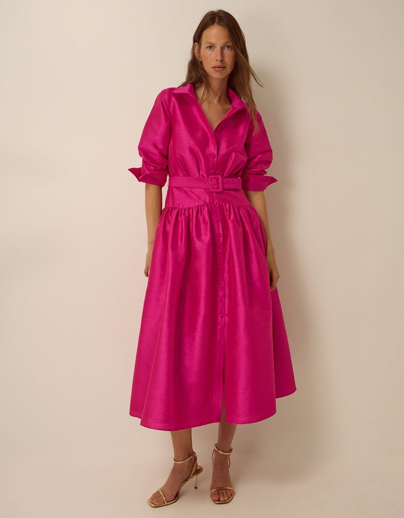 a model wears a hot pink belted midi shirt dress.