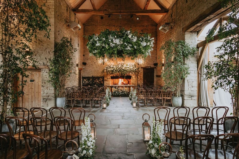 interior of a modern barn dressed with foliage and set-up for a wedding ceremony.