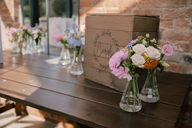 a card box on a table alongside vases of flowers.