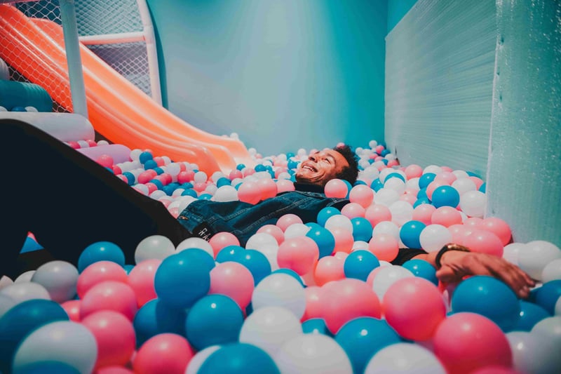 a man smiling as he falls back into a ball pit.