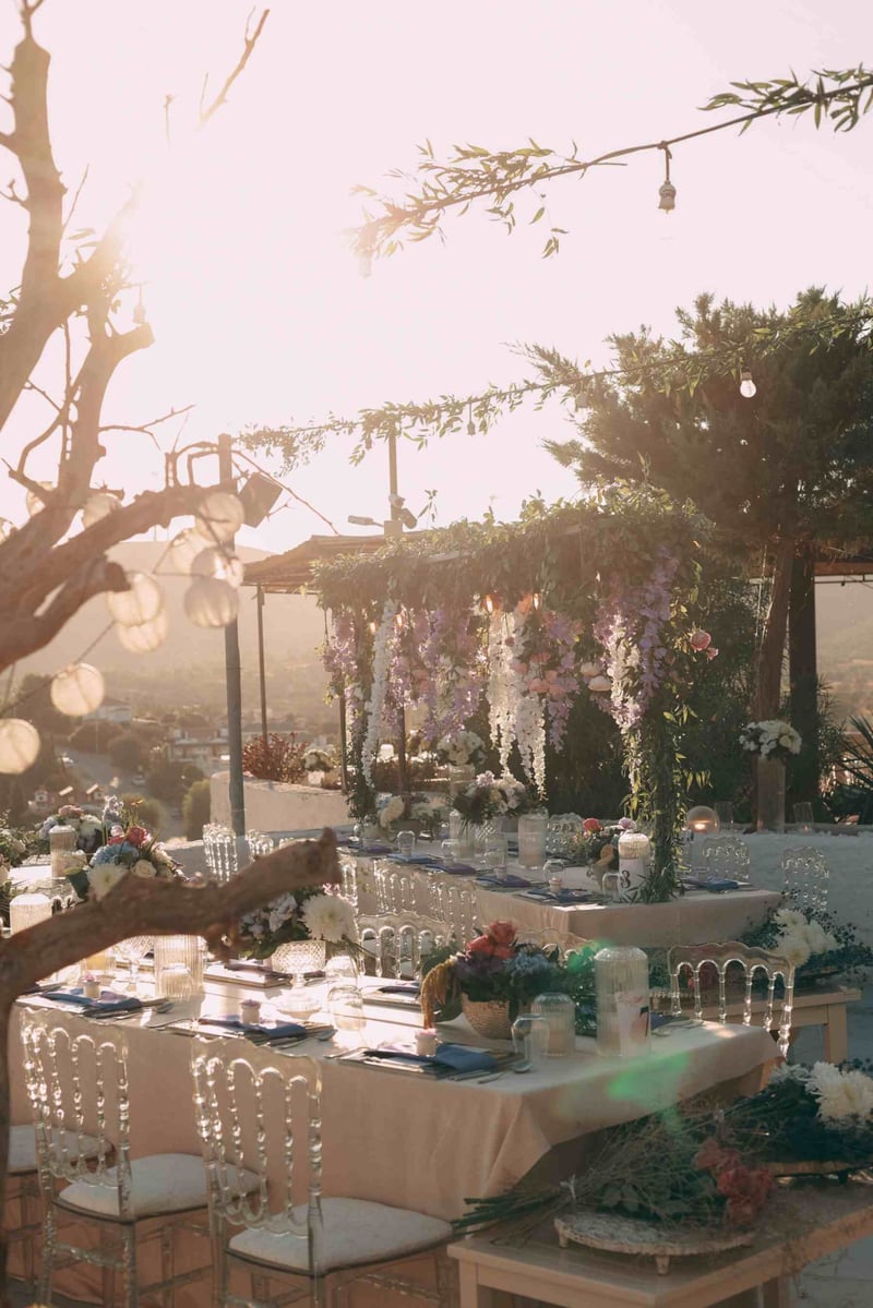 Beautifully decorated outdoor wedding reception setup at sunset with floral arrangements and scenic views