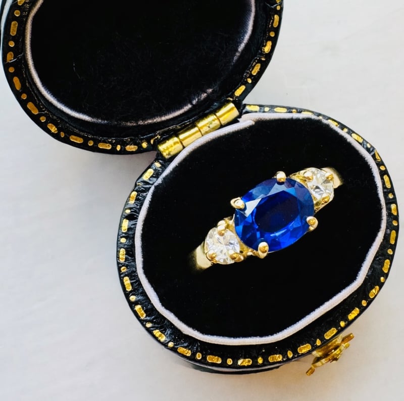 an art deco style sapphire engagement ring in a vintage box.