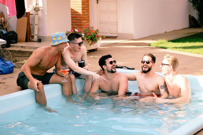 a group of men on a stag do abroad in a hot tub laughing and drinking. 