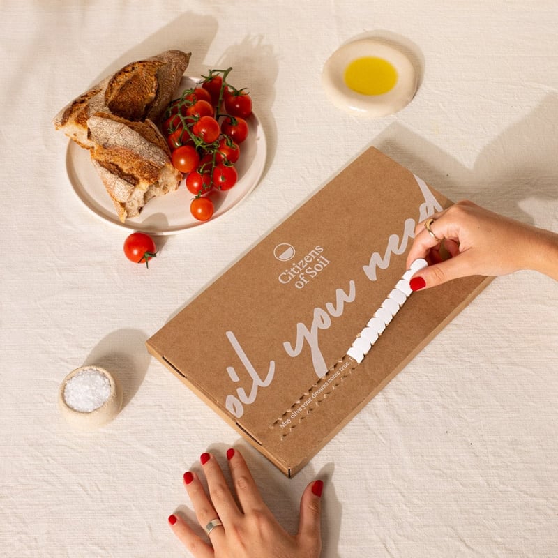 close-up of a hand unboxing an olive oil subscription gift.