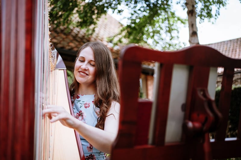 a harpist smiles as she performs outdoors.