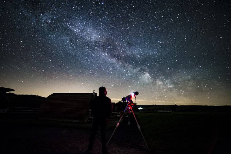 a person with a telescope looking up at the night's sky.