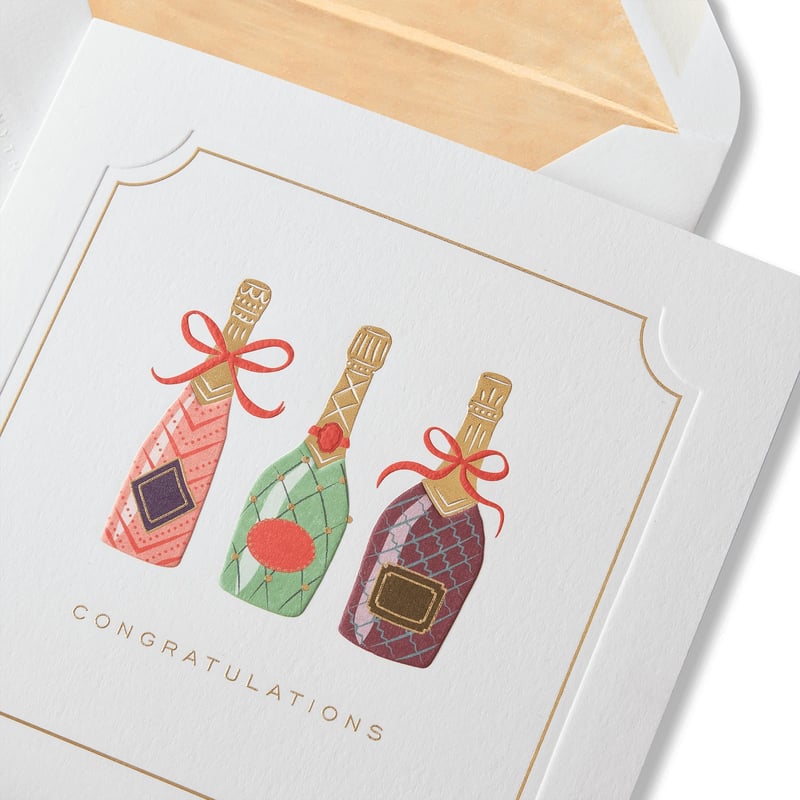 a wedding card with three champagne bottles on the front.