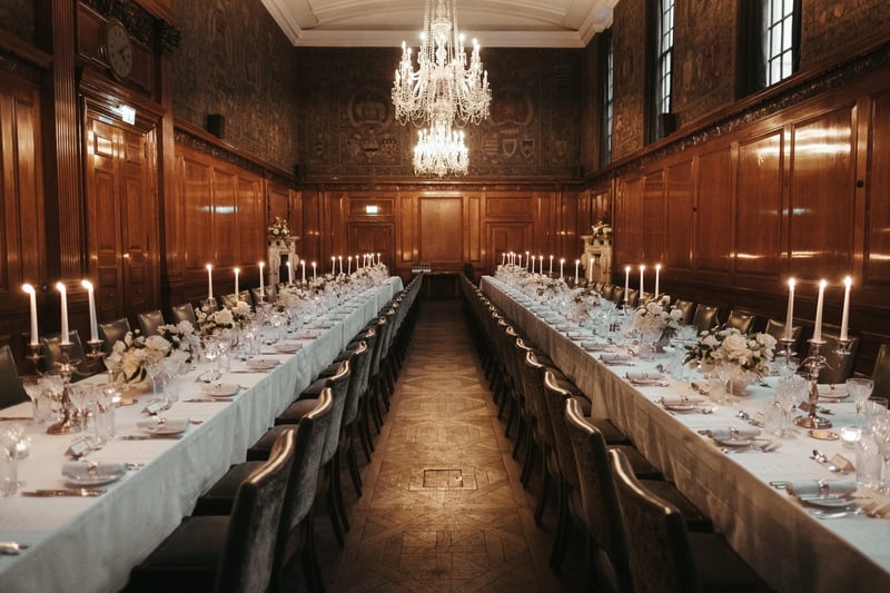 interior of a 1920s style wood-panelled room set up for a wedding breakfast with long tables.