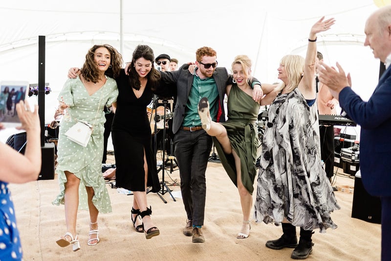 party guests dance in a line inside a marquee.