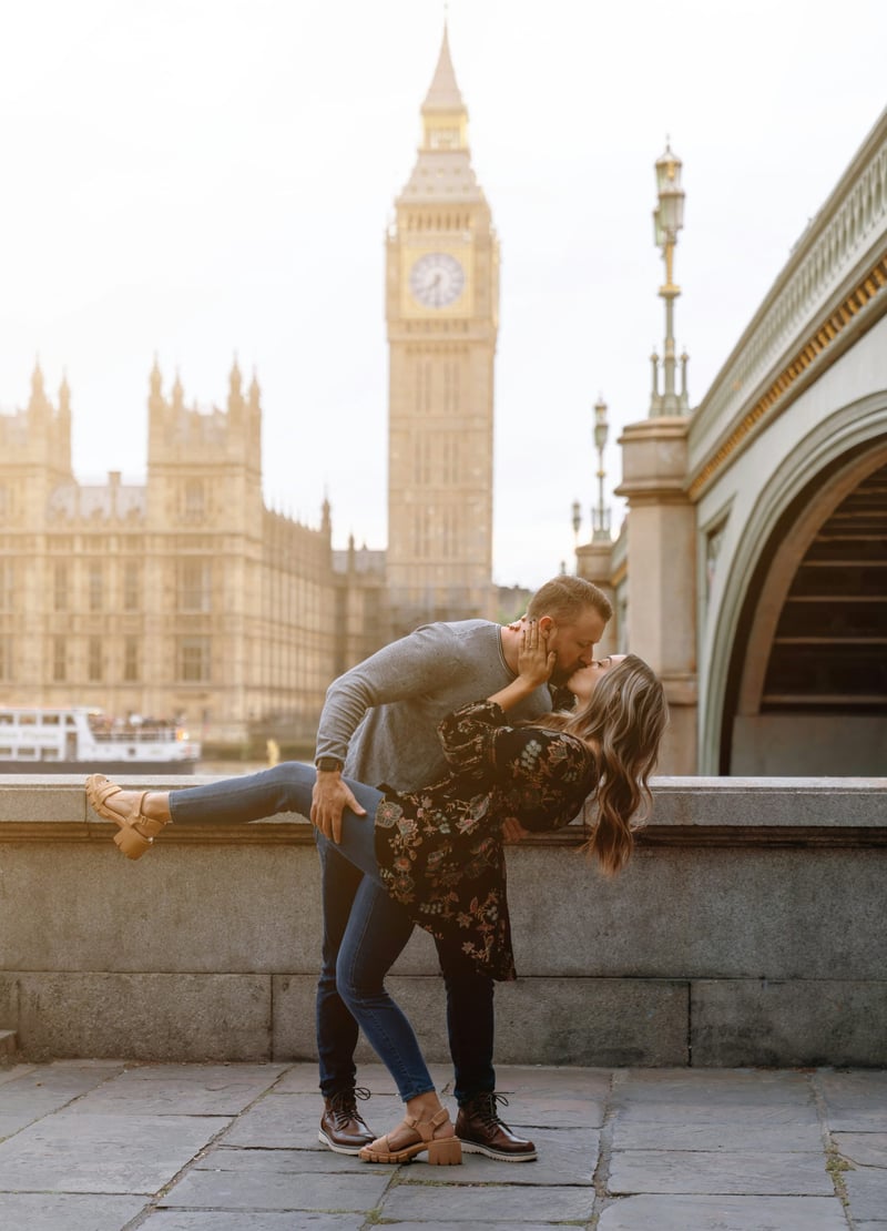 a man and woman kiss in London with Big Ben in the background.