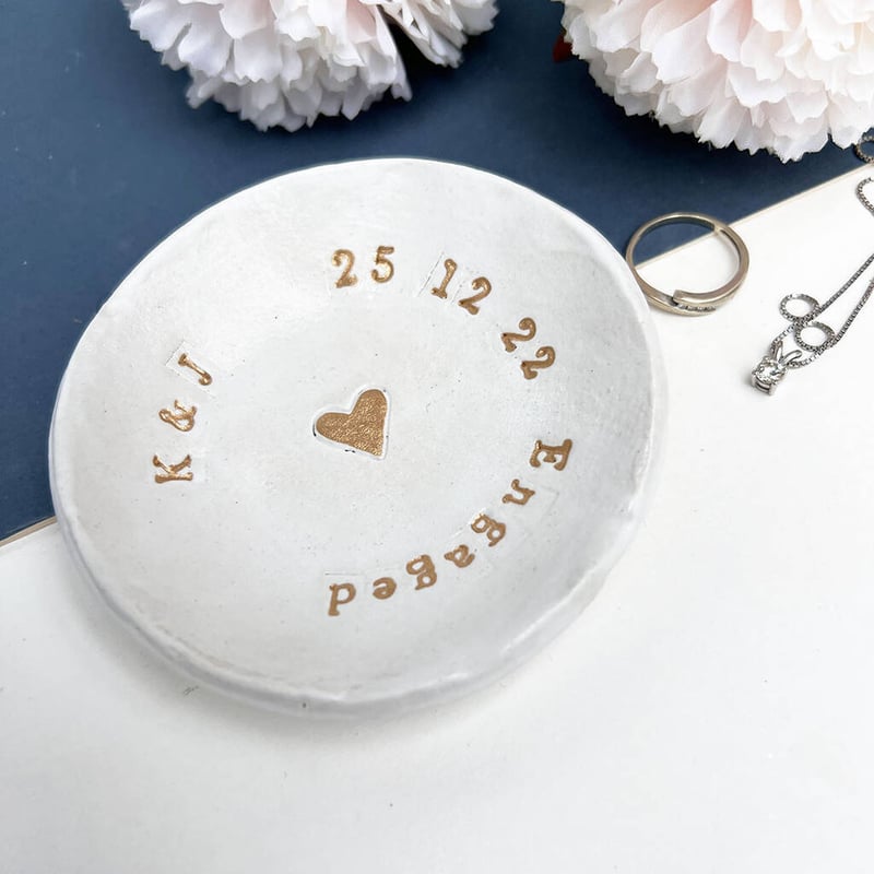 a white ring dish engraved with gold text.