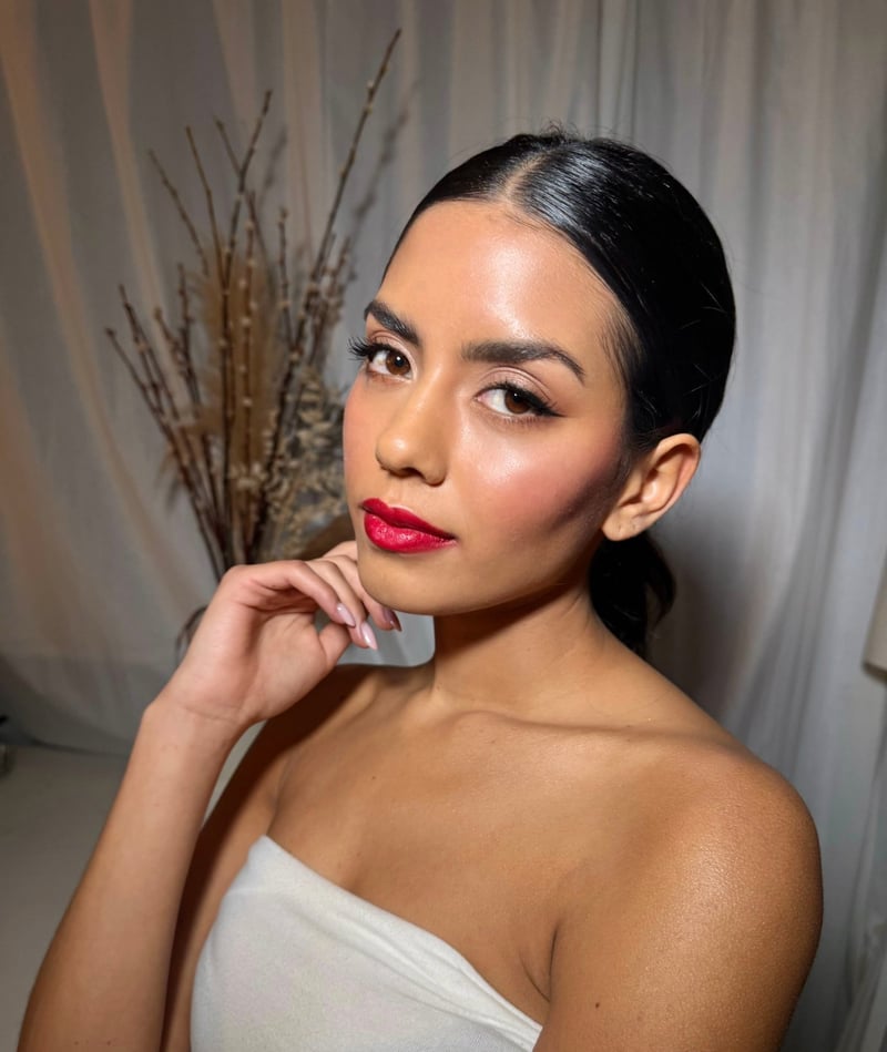 a model with dark hair and a bold red lip. her hair is styled into a slick back bun.