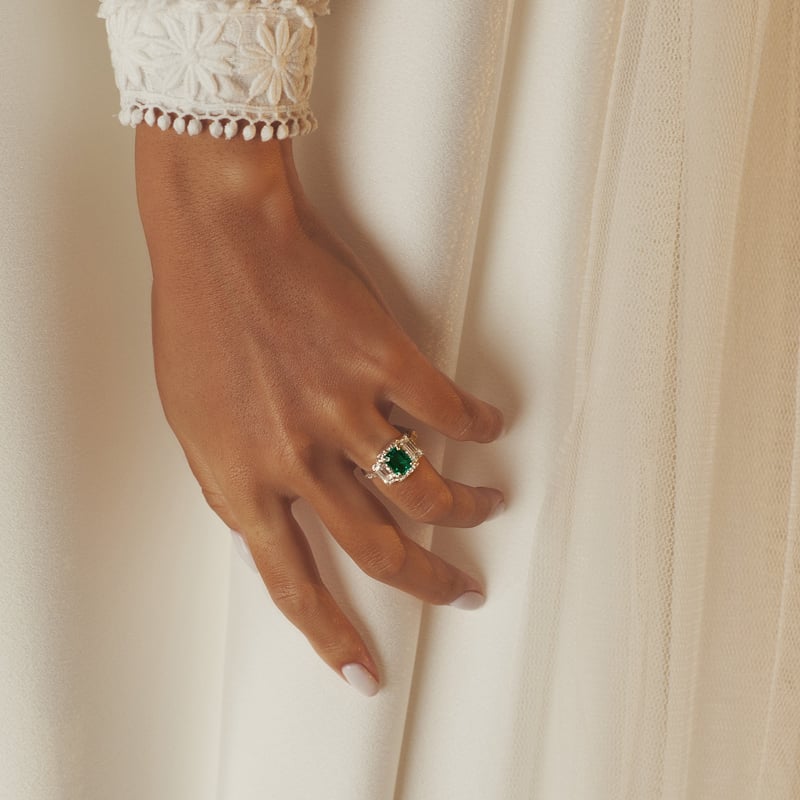 a bride wearing a white gold and emerald engagement ring.