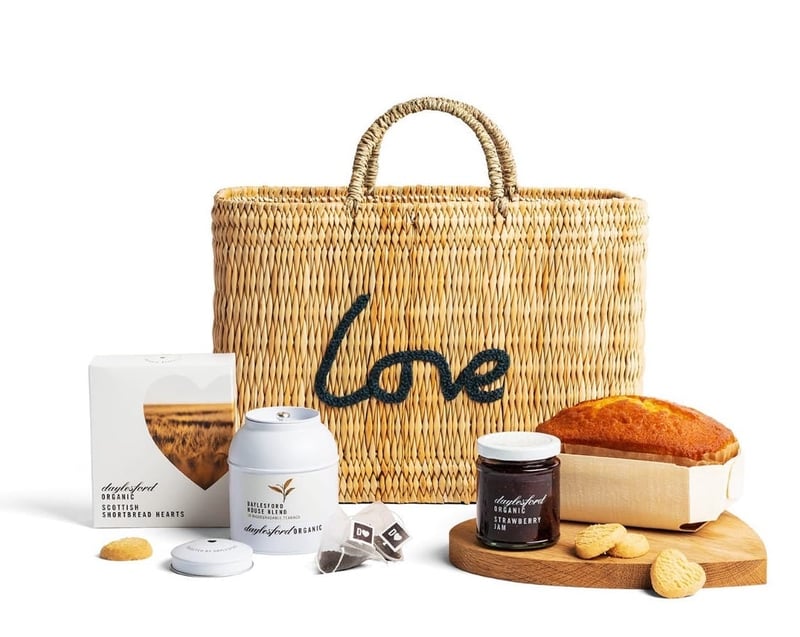 a hamper basket with the word 'love' on the front and an array of teatime food and drink items.