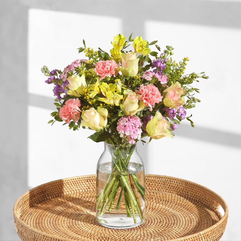 a bouquet of pastel-coloured flowers in a glass vase.