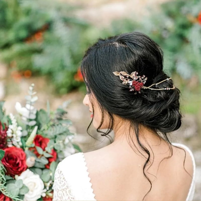 a bride with dark hair and a messy updo has her back to the camera. In her hair is a delicate hair vine.