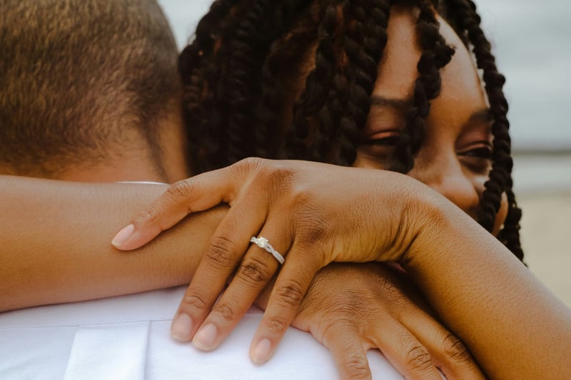 a black woman hugging her partner with a close-up of her engagement ring.