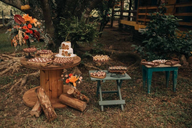 Charming outdoor dessert setup with rustic cakes and flowers, perfect for weddings
