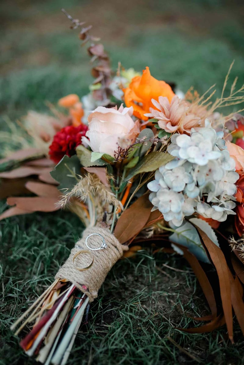 Colorful autumn wedding bouquet with rings on grass, ideal for romantic themes.