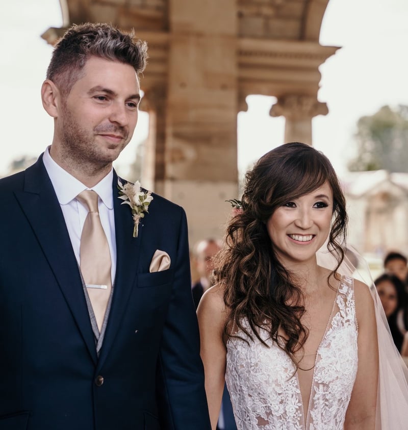 a bride with long brunette hair styled into a curly side pony stands with her groom.