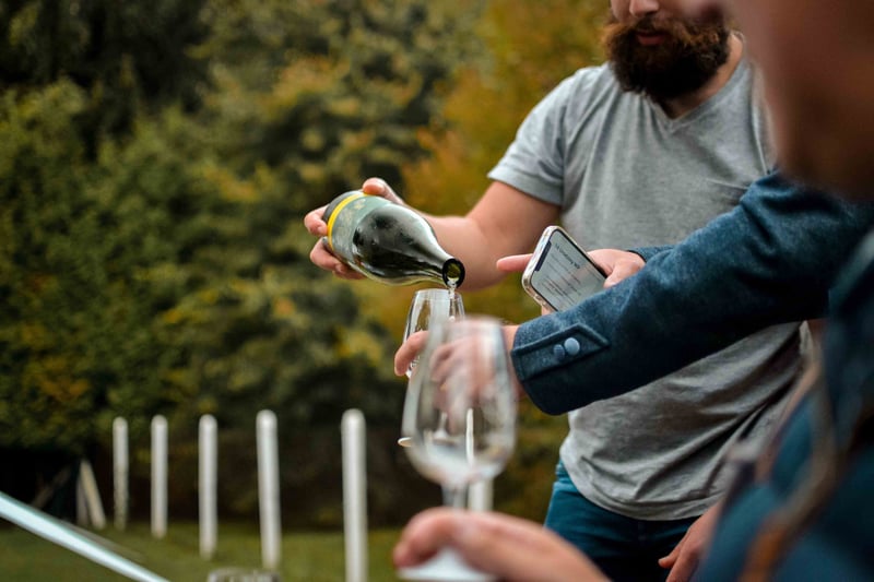 a man pours wine into a glass at a wine tasting stag do.