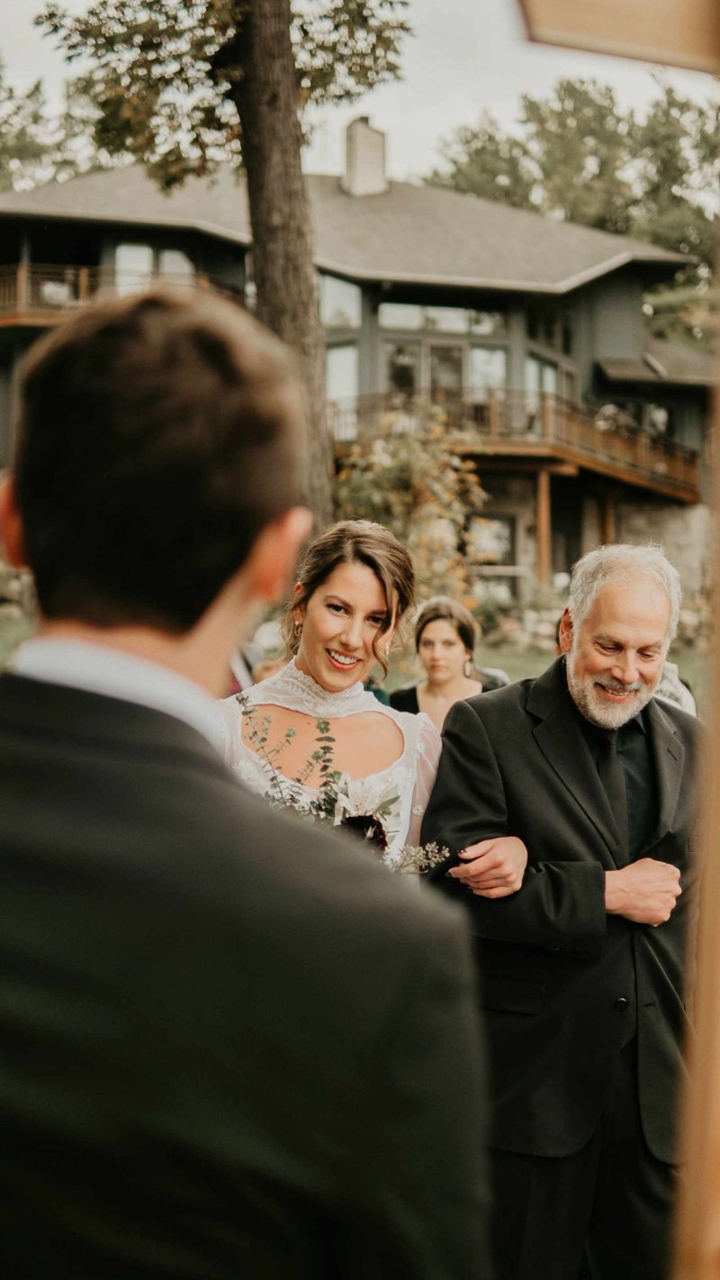 Bride walking with father at outdoor wedding.